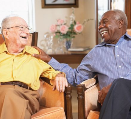 Two Senior Men Enjoying a conversation while sitting in the community room